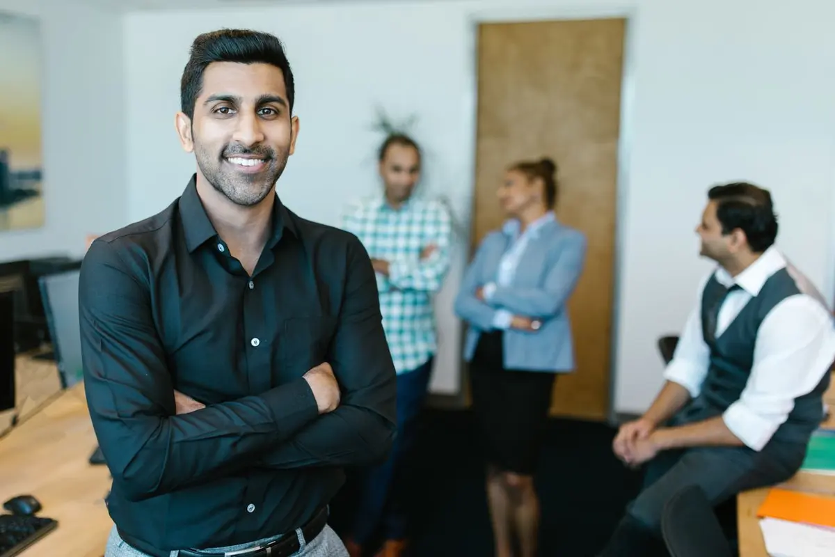 Confident professional standing in a modern office with his team