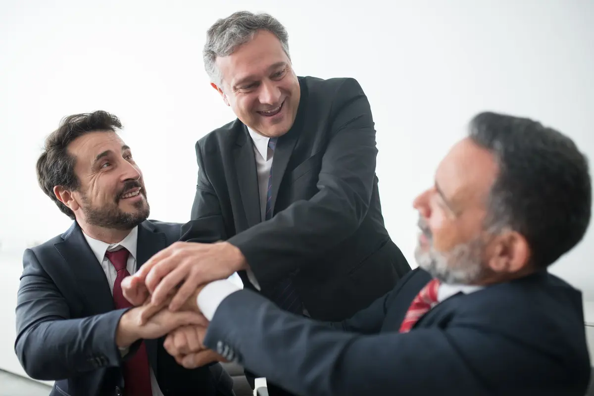 Three business leaders celebrating a new partnership